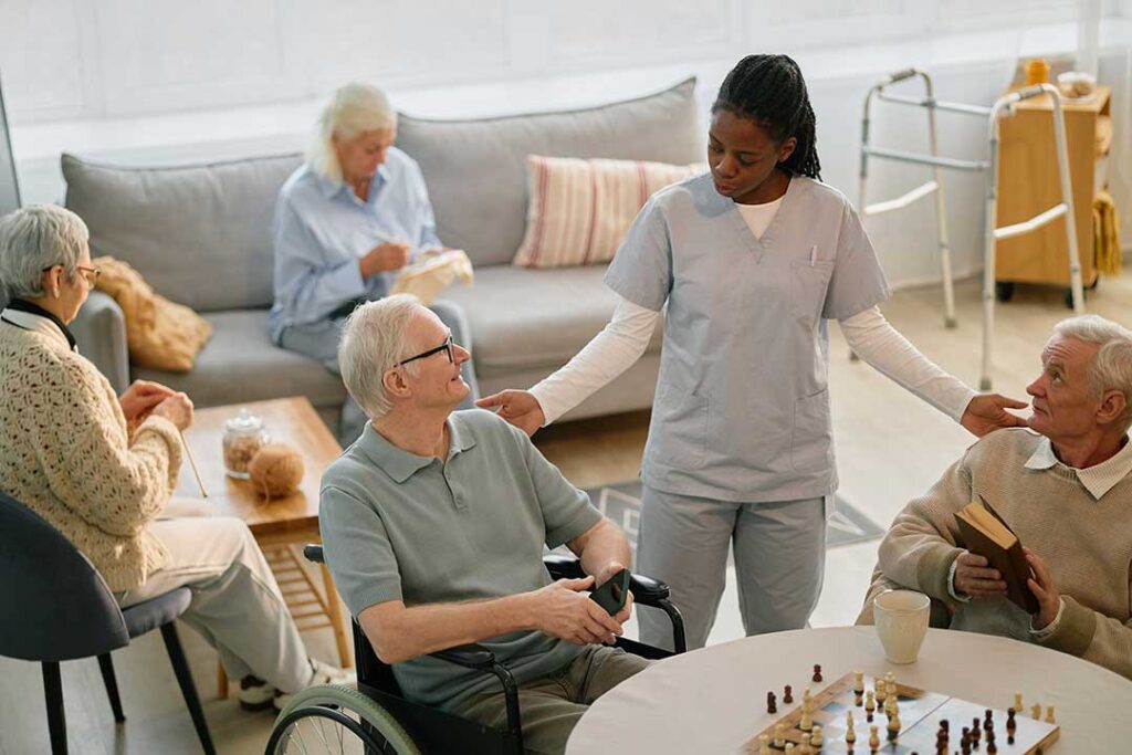 Older adult arranging photographs and clothing in a new assisted living room with family support.