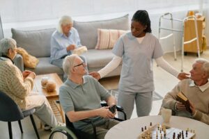 Older adult arranging photographs and clothing in a new assisted living room with family support.